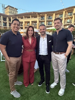 Four people in semi-formal attire stand together in a courtyard.