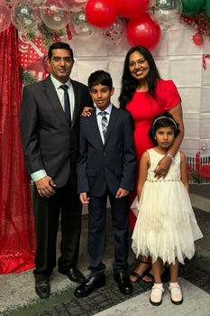 A young man and woman pose with two school-aged children, a boy and a girl.