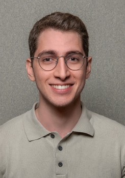 A portrait of Dr. Chammas. He has light skin, short brown hair, and wears large round glasses.