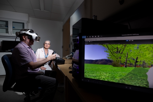 Research sits with participant using virtual reality headset.
