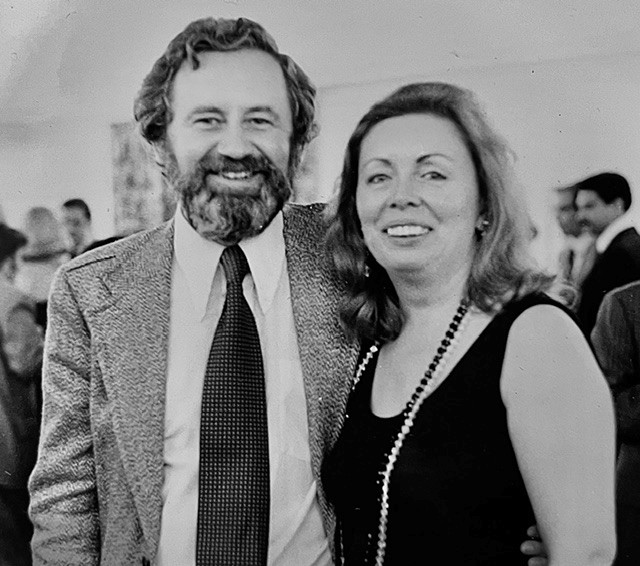 a black and white photo of the couple dressed up looking at camera