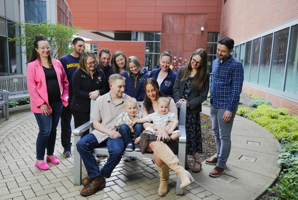 Hunter and his family sit on a bench outside Golisano Children's as members of the Clinical Trials Team and his care team surround them.