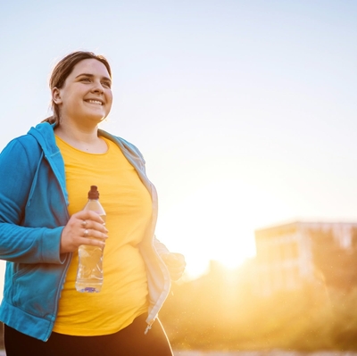 Smiling woman holds water bottle while on the move outside