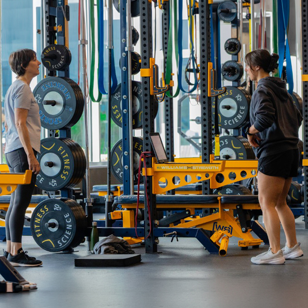 A fitness trainer teaches an adult a movement at fitness science class
