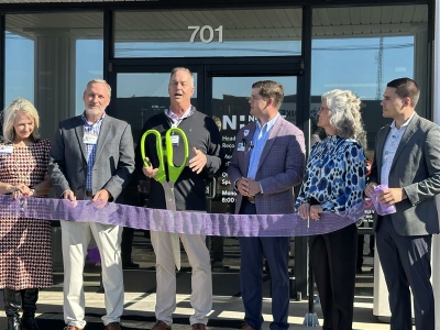 Novant Health team outside new clinic, Dr. Kissenberth holding ceremonial scissors for ribbon cutting