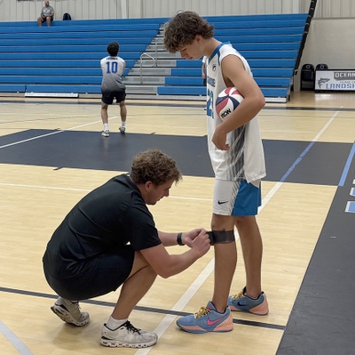 Trainer assists student athlete at OCA