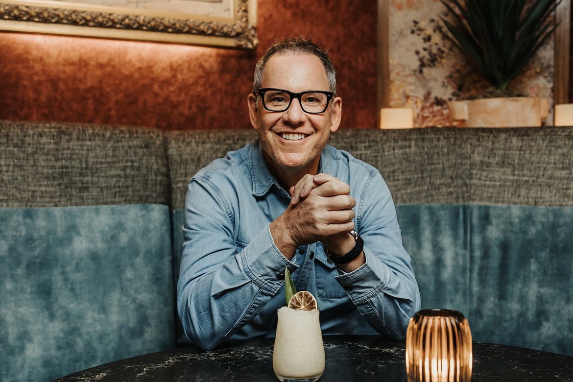 Sam Fox profile photo at a restaurant booth with a drink