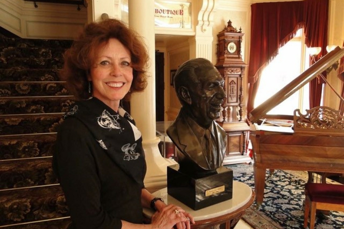 Peggie Fariss smiling for a photo next to Walt Disney sculpture