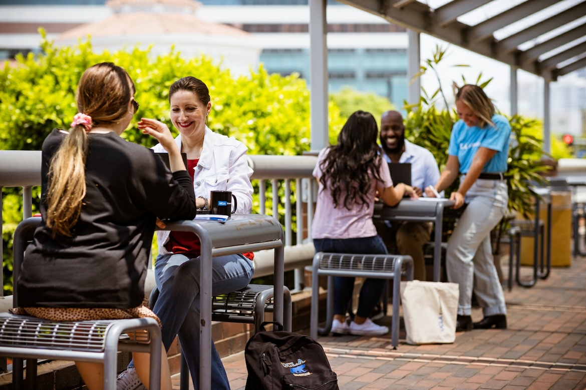 People are sitting outside while working on their laptops for UCLA Extension