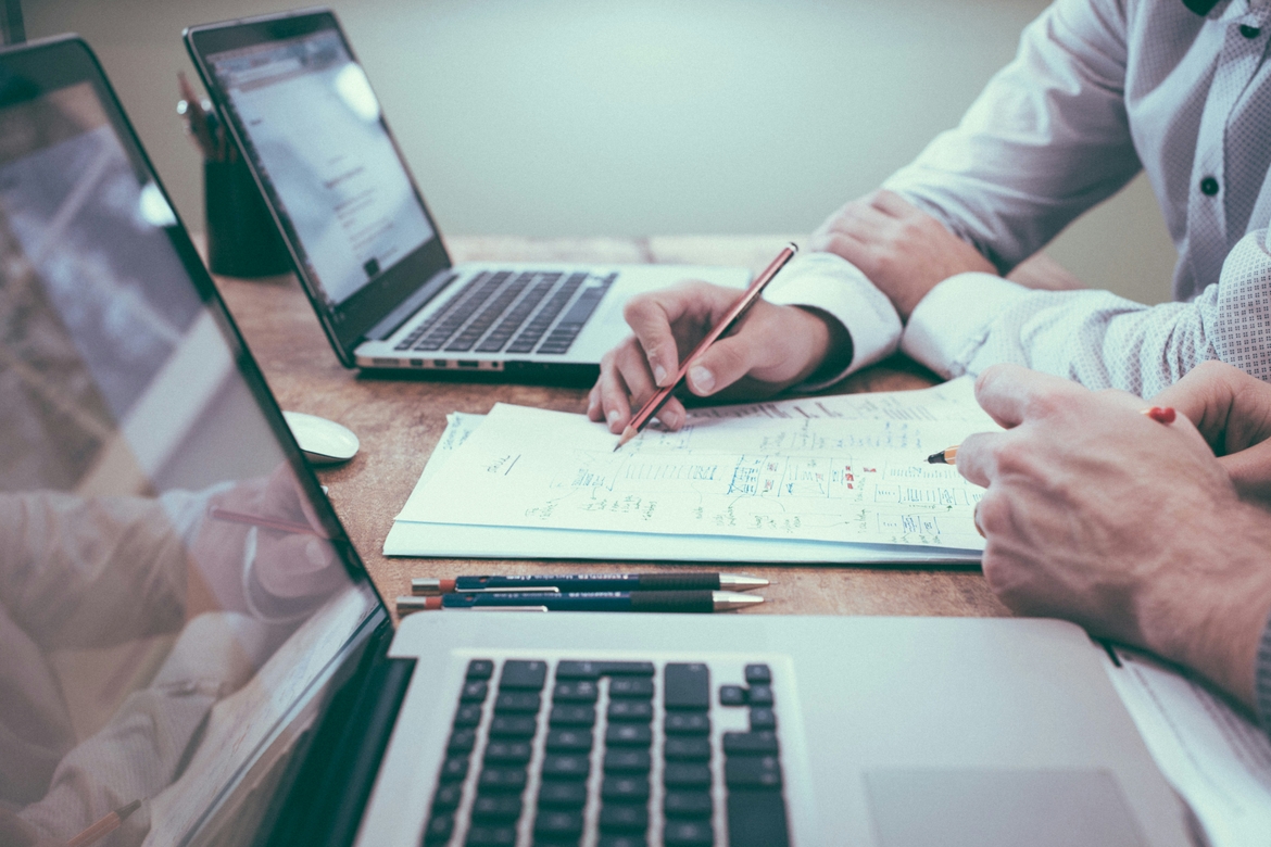 Hands working on laptops and financial papers