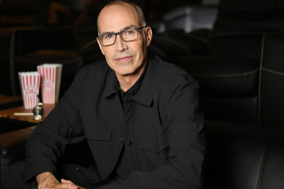 Scott Edwards in a movie theatre with popcorn buckets beside him.