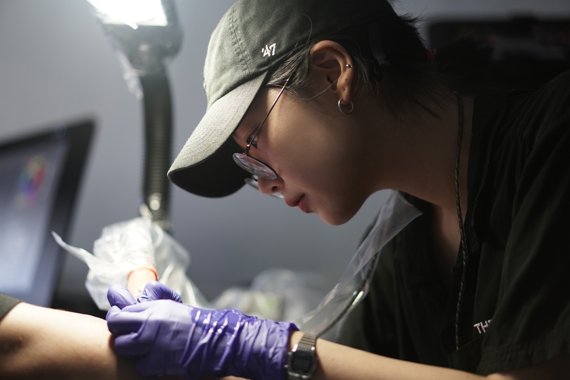K Tak works closely on a tattoo for a client