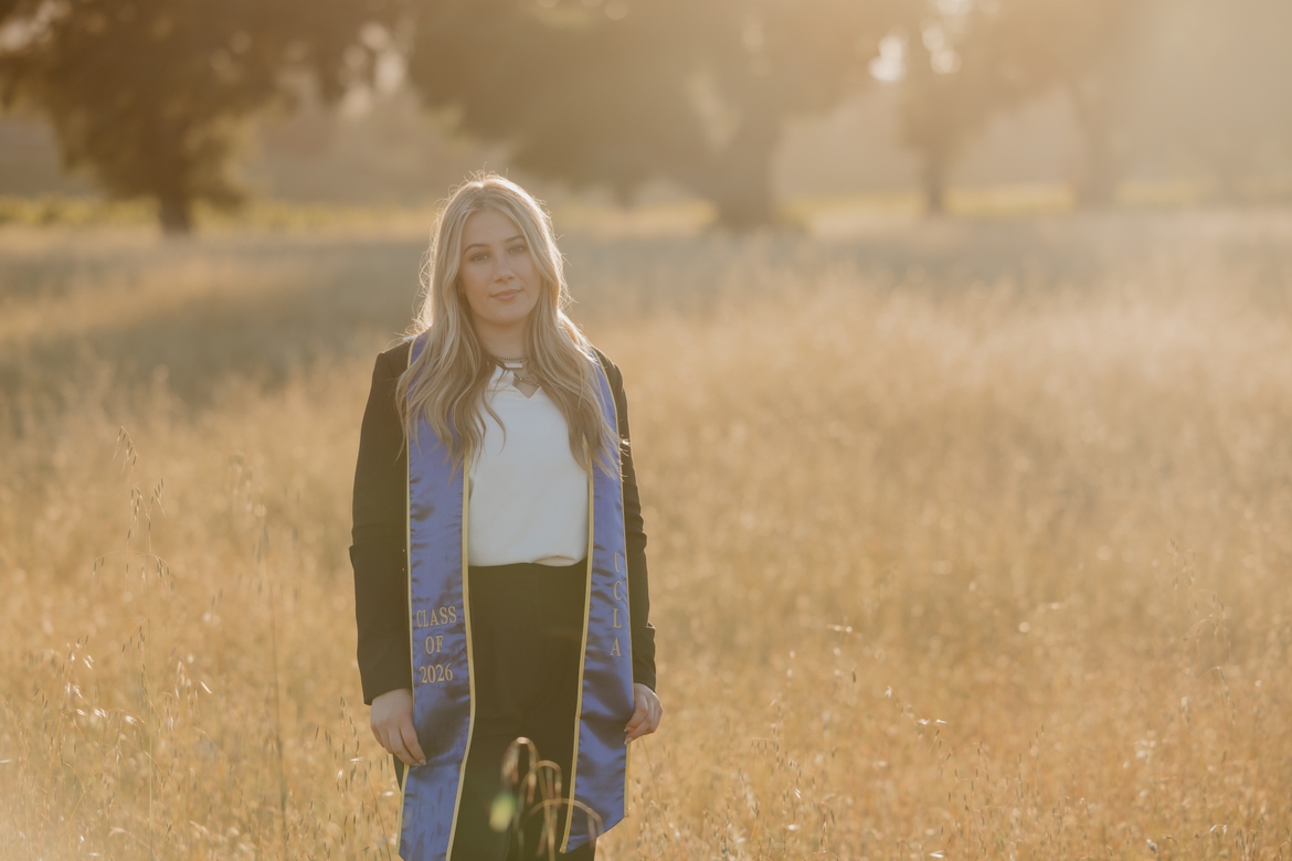 Mia Goldman poses in a field with her UCLA graduation sash