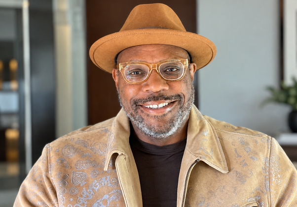 Andre Hardy in a brimmed hat, glasses and coat
