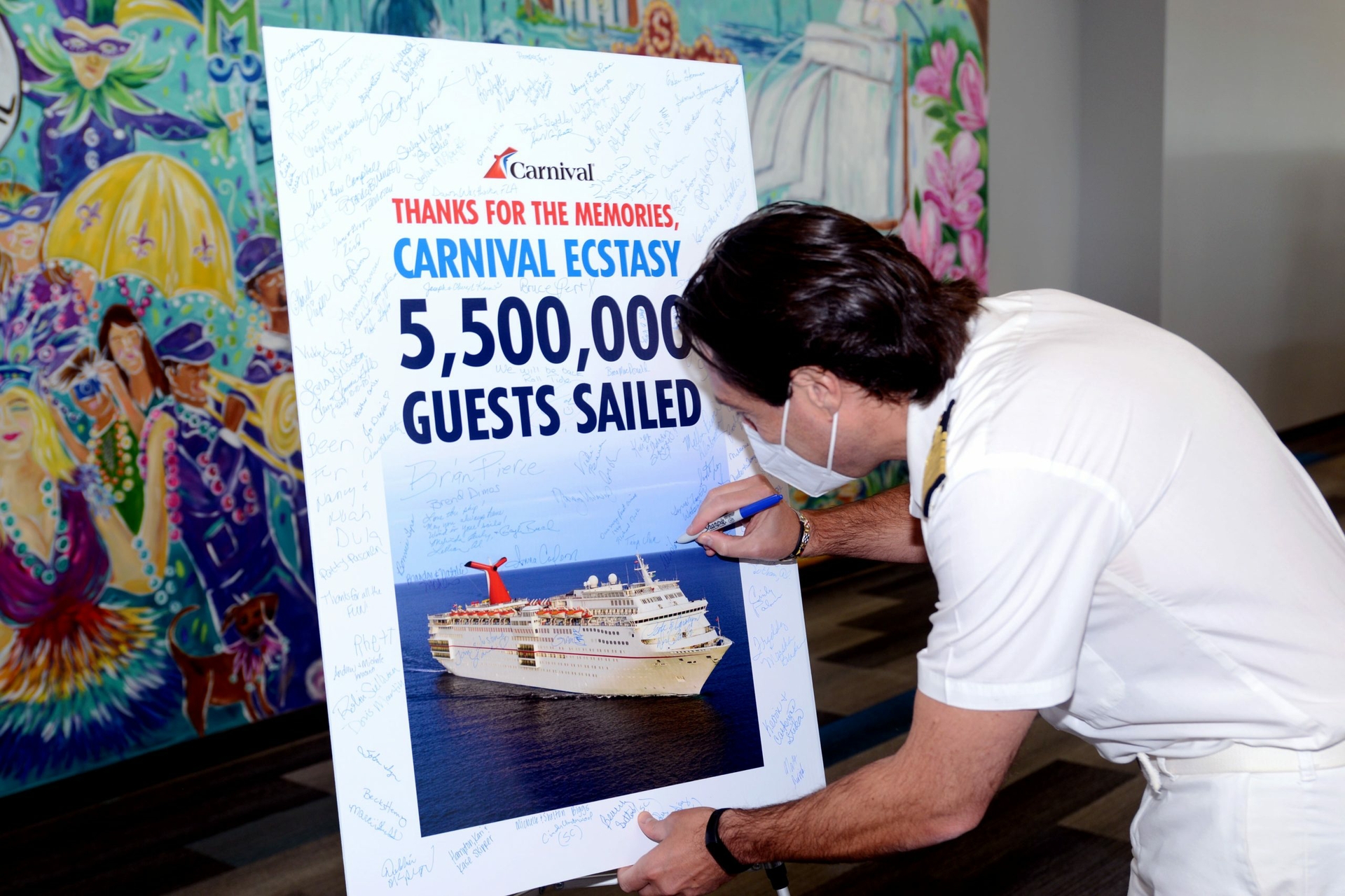 Inside the Mobile, Alabama cruise terminal, Capt. Michele Coppola and Carnival Brand Ambassador John Heald join guests in signing a poster ahead of Carnival Ecstasy’s final voyage on Monday, Oct. 10.