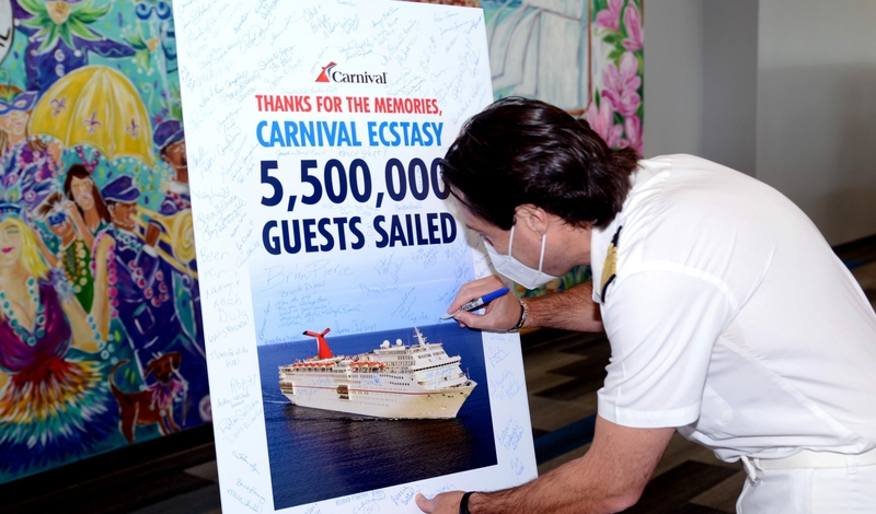 Inside the Mobile, Alabama cruise terminal, Capt. Michele Coppola and Carnival Brand Ambassador John Heald join guests in signing a poster ahead of Carnival Ecstasy’s final voyage on Monday, Oct. 10.