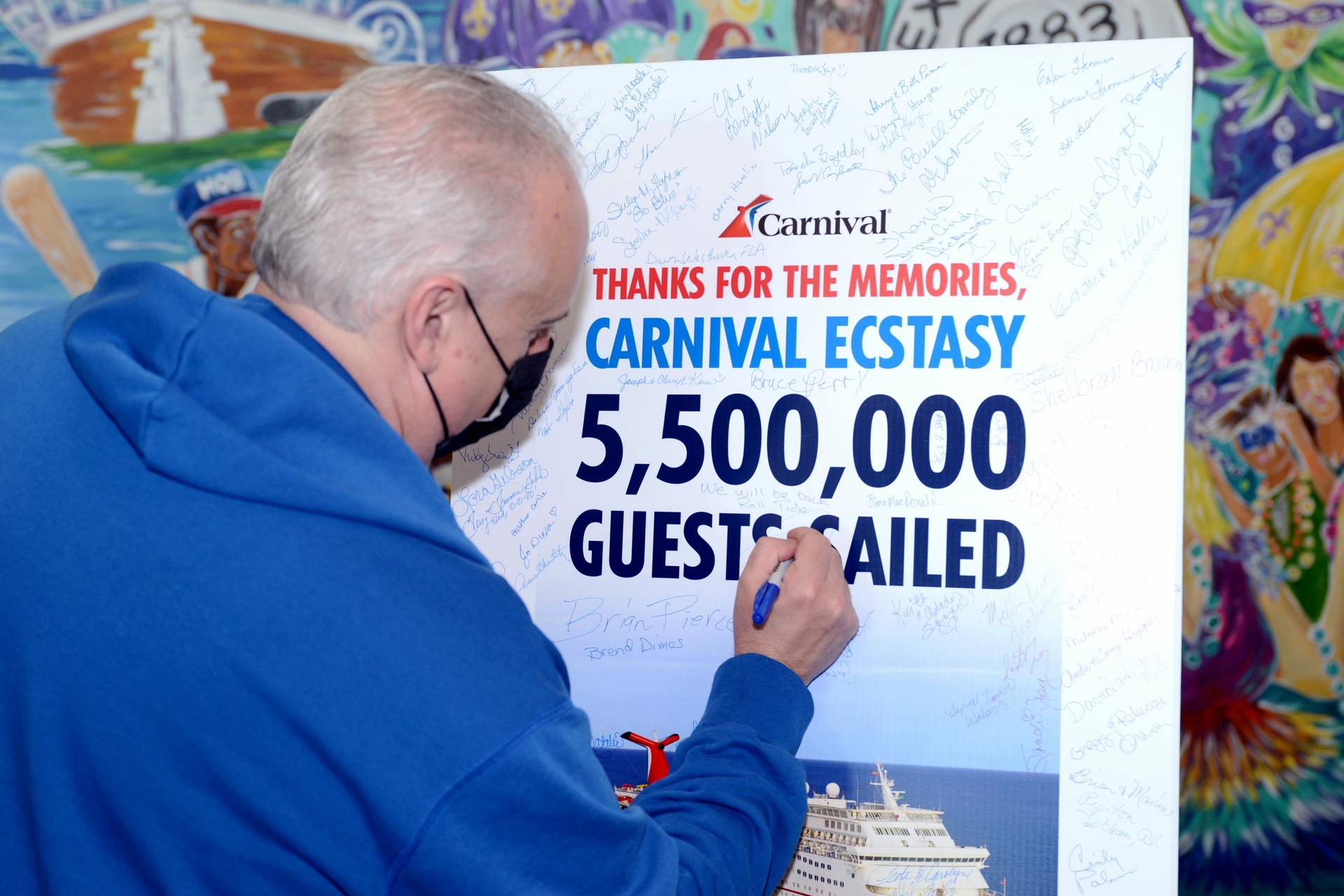 Inside the Mobile, Alabama cruise terminal, Capt. Michele Coppola and Carnival Brand Ambassador John Heald join guests in signing a poster ahead of Carnival Ecstasy’s final voyage on Monday, Oct. 10.