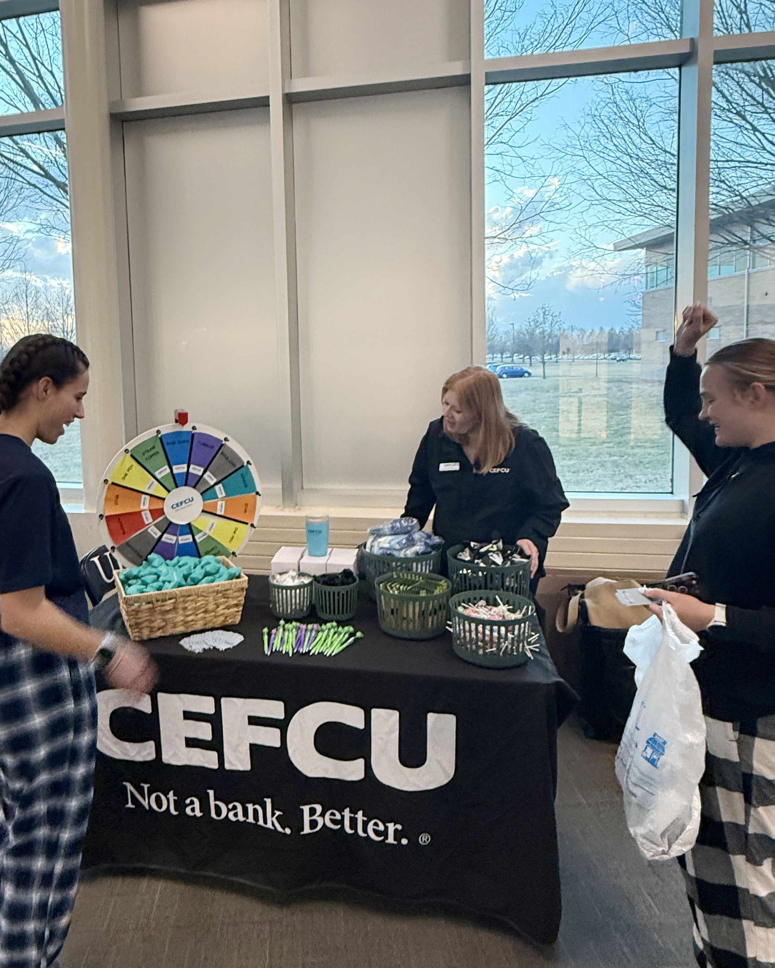 CEFCU employee speaking with UIS students at an information table during the basketball games.