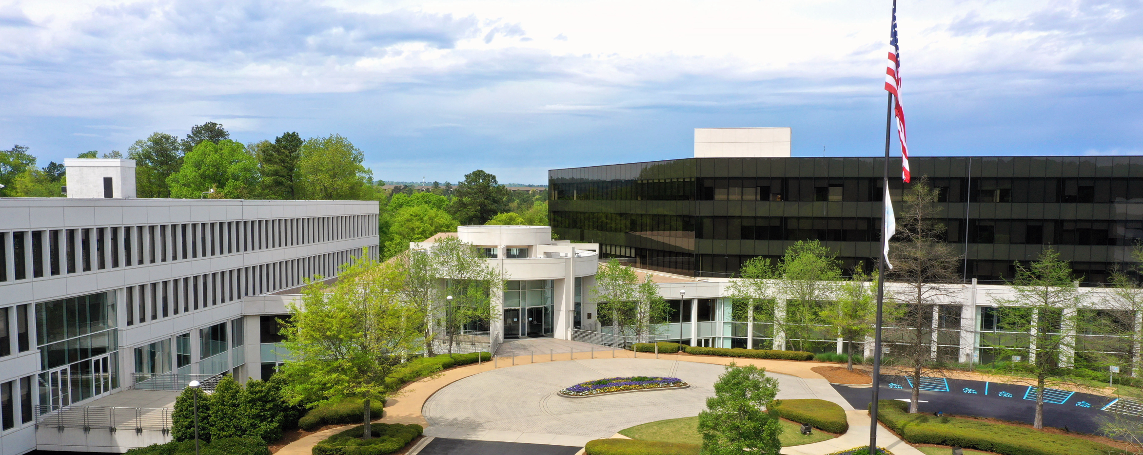 Exterior photograph of BlueCross BlueShield Alabama corporate headquarters, surrounded by green trees and an American flag in the foreground.