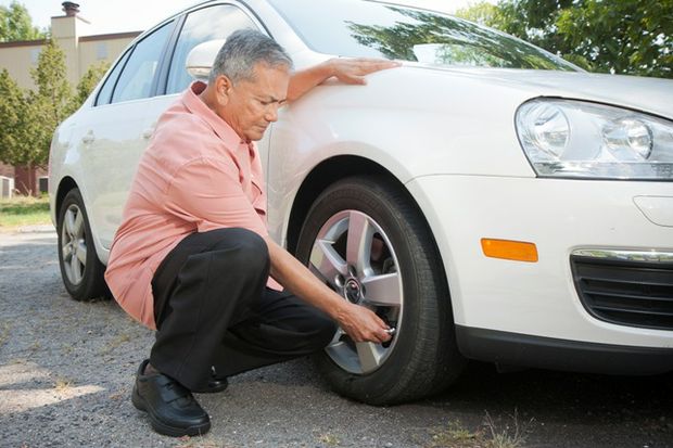 Man uses tire pressure gauge