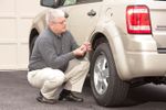Senior driver looking at tire pressure gauge