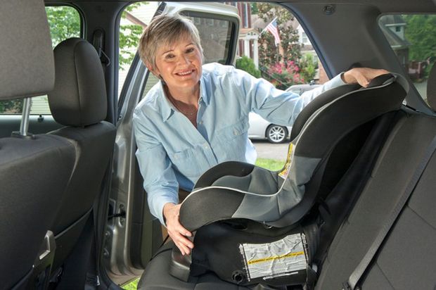 Woman grandma puts carseat in car