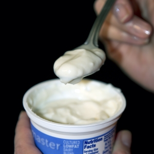 Yogurt LowFat plain held with spoon verticle