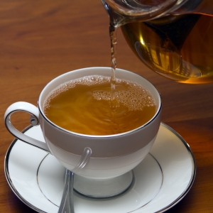 Green Tea poured into cup from glass tea pot Horizontal