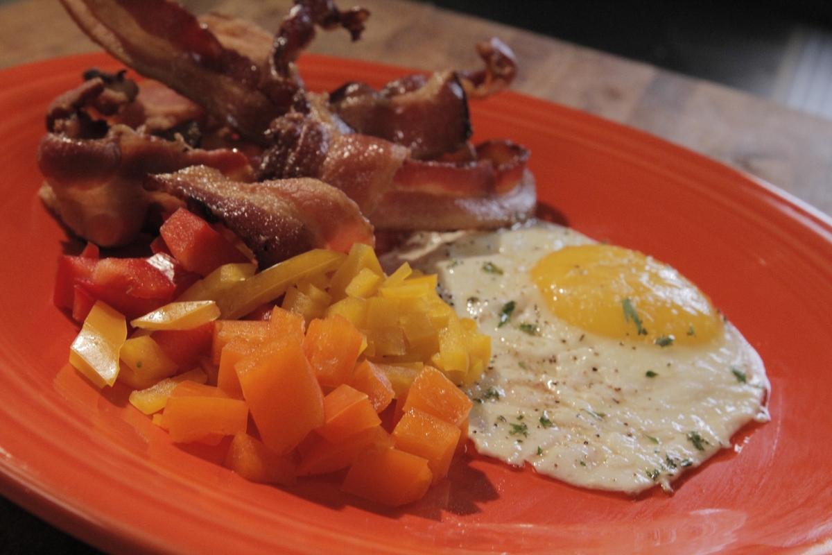 Breakfast plate close up - fried egg, bacon, peppers
