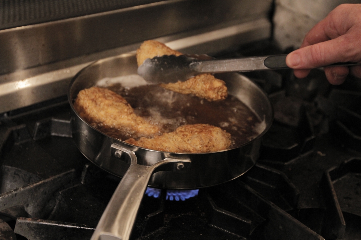 Chicken thighs being placed in frying pan