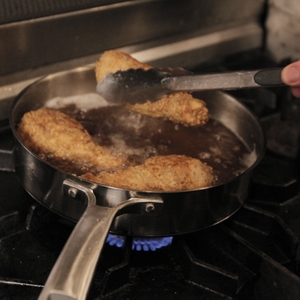 Chicken thighs being placed in frying pan