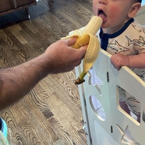 Dad feeding toddler banana
