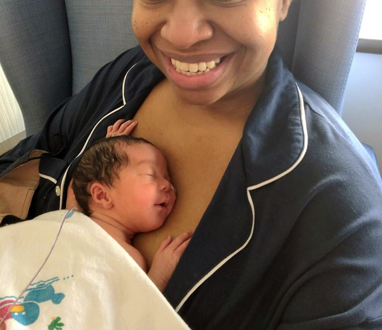 A women smiling with her newborn baby laying on her chest