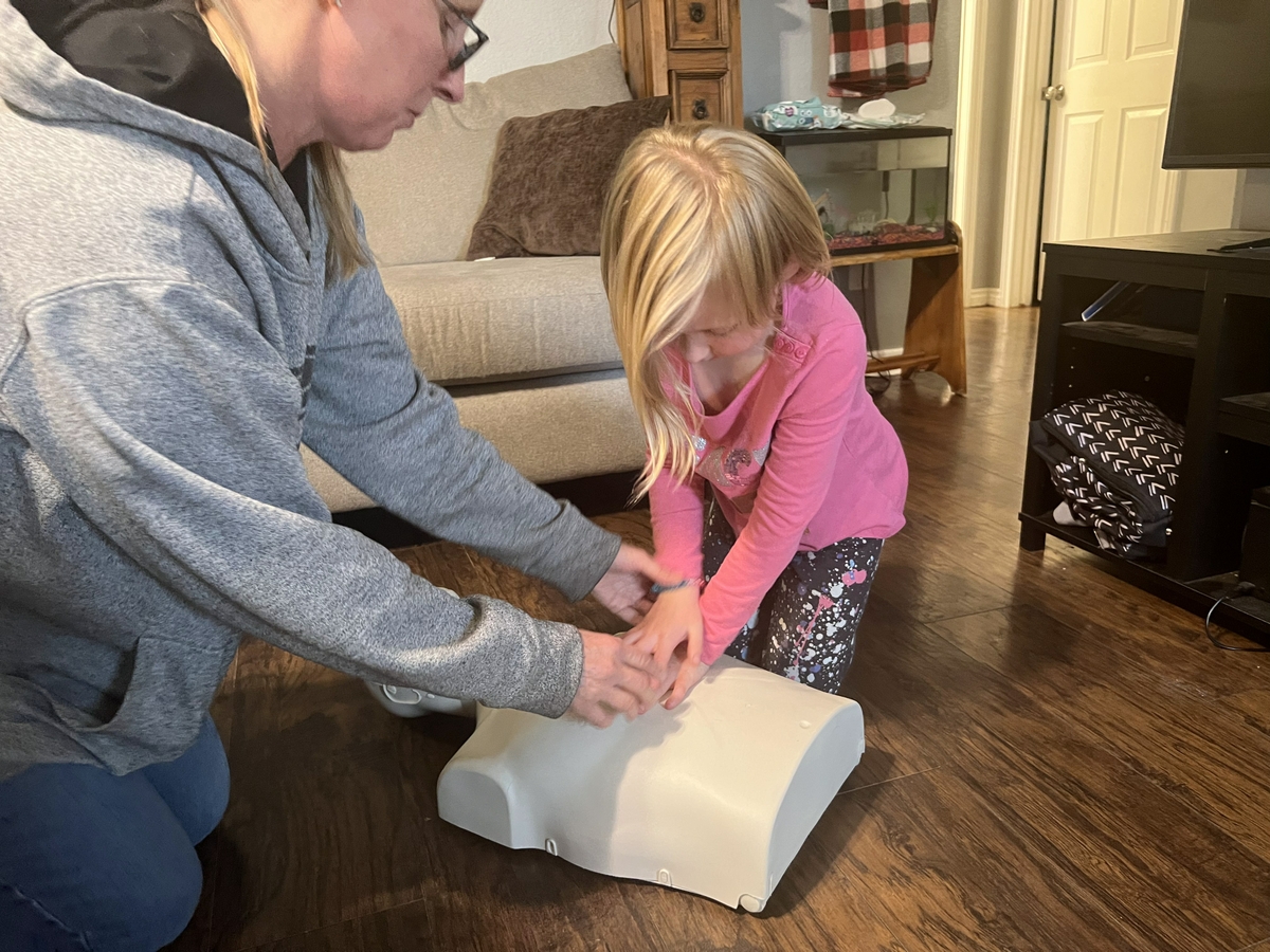 Mom showing daughter CPR hand placement