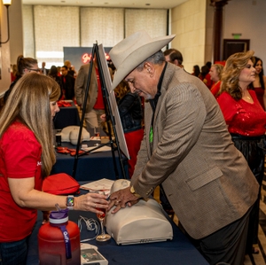 A guest practices Hands-Only CPR at the Tarrant Country Go Red for Women movement