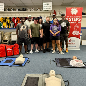 Men and women pose with CPR Kits and CPR Mannequins