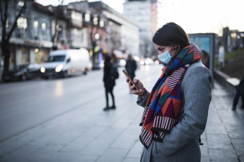 Woman With Mask Using Phone On The Street.